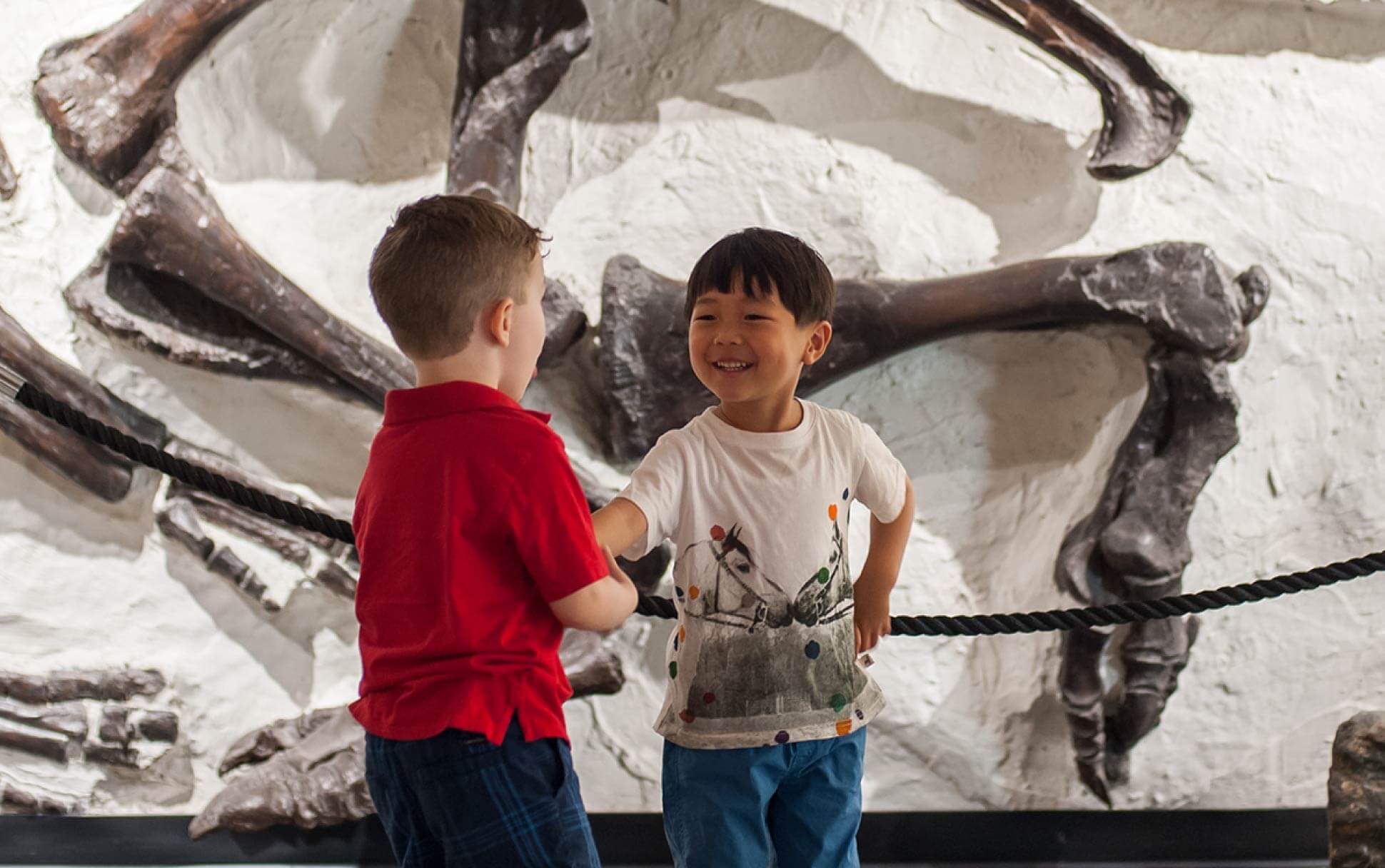 Kids stand in front of a dinosaur bone at the Pacific Museum of Earth at UBC Vancouver