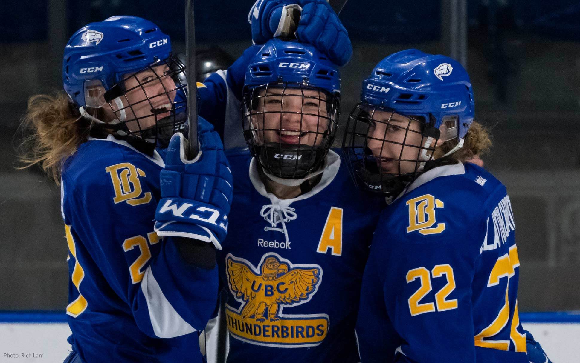 Three players from the UBC Thunderbirds Women's Hockey Team celebrate a goal.
