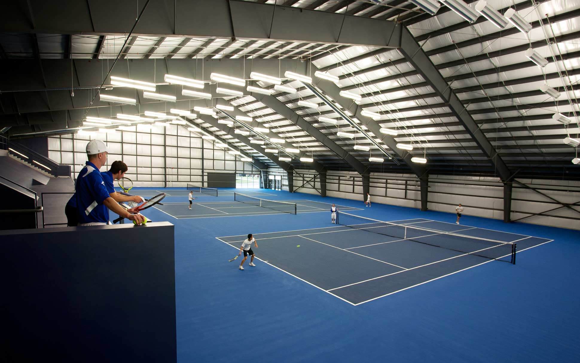Two people play a game of tennis on an indoor court at the UBC Tennis Centre