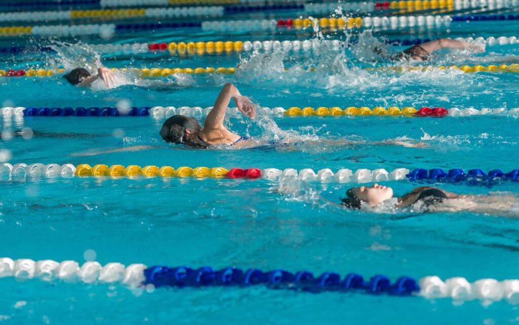 Three people swim laps at the UBC Aquatic Centre in Vancouver