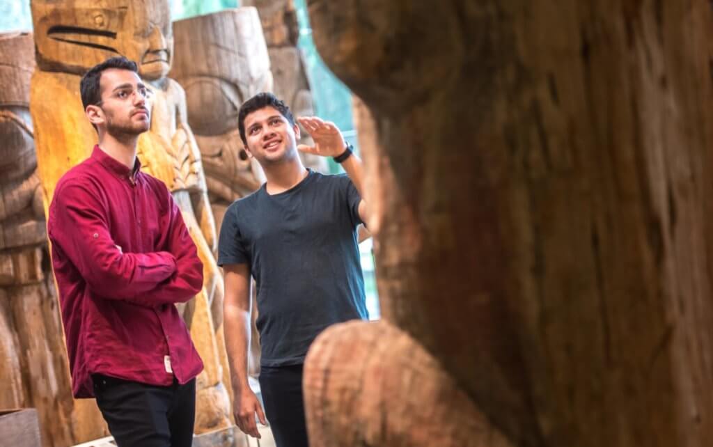 Two people look at Indigenous art in the Museum of Anthropology (MOA) at UBC Vancouver.